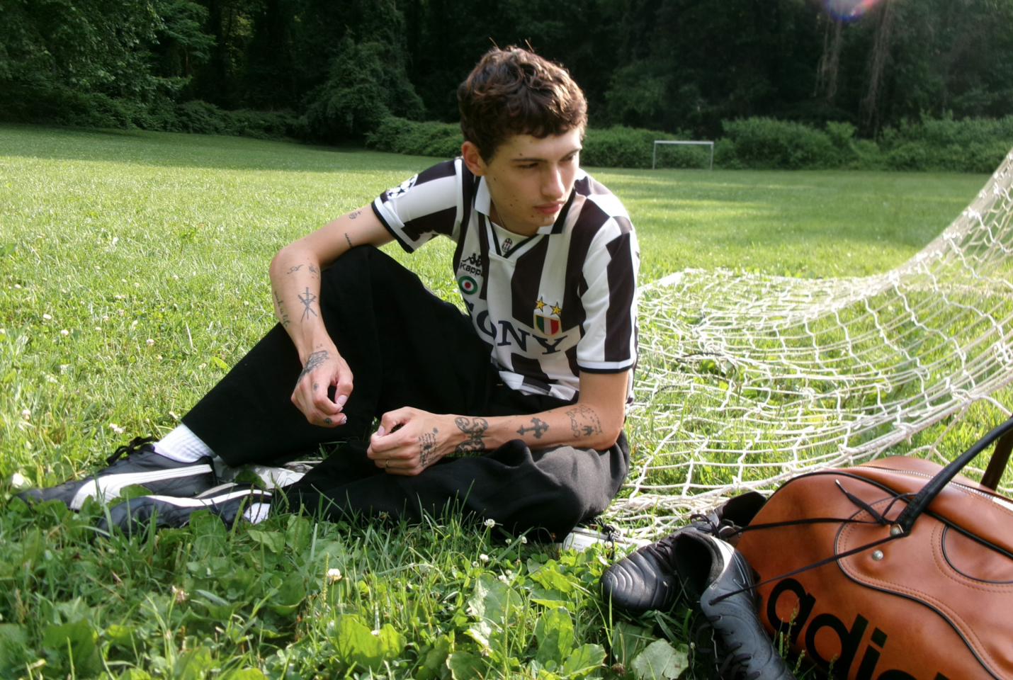 Musician Glaive sitting in front of football goals wearing a football top.